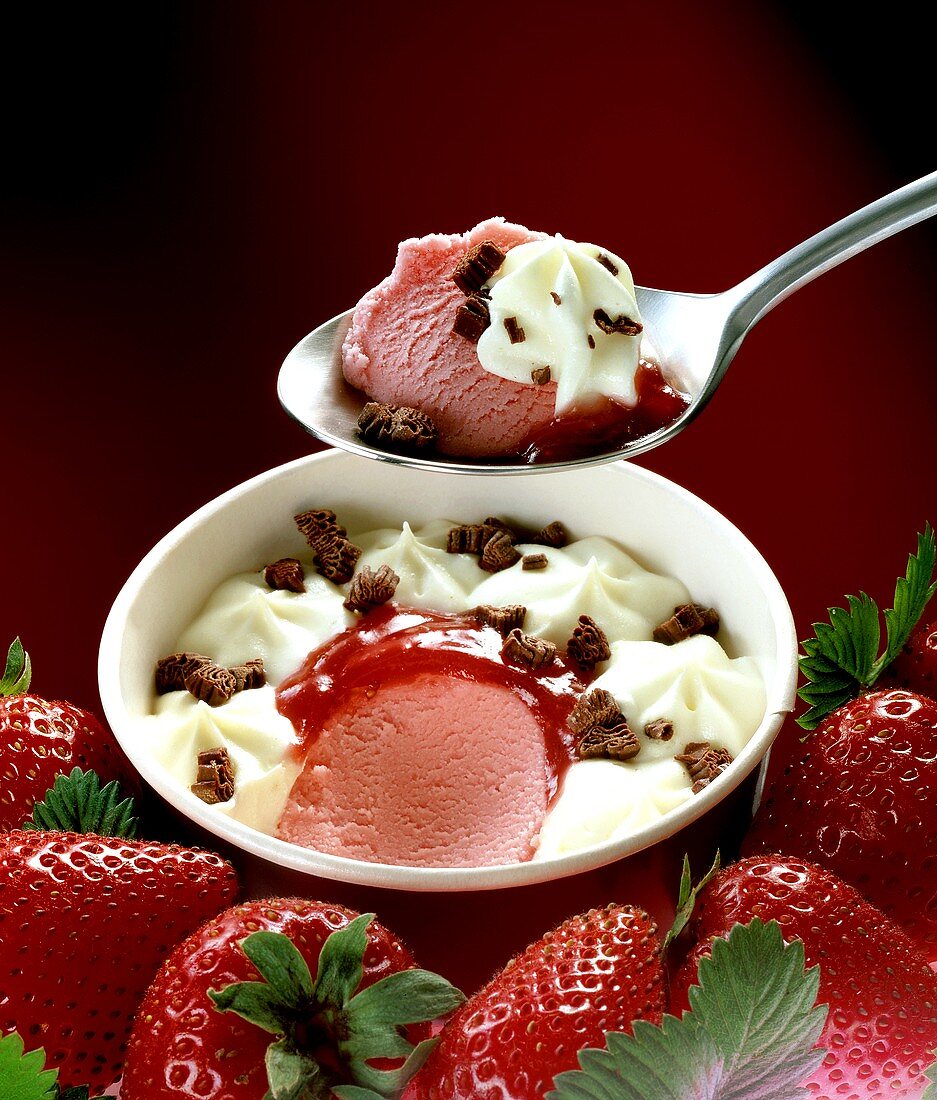 Strawberry ice cream with cream in cardboard tub and on spoon