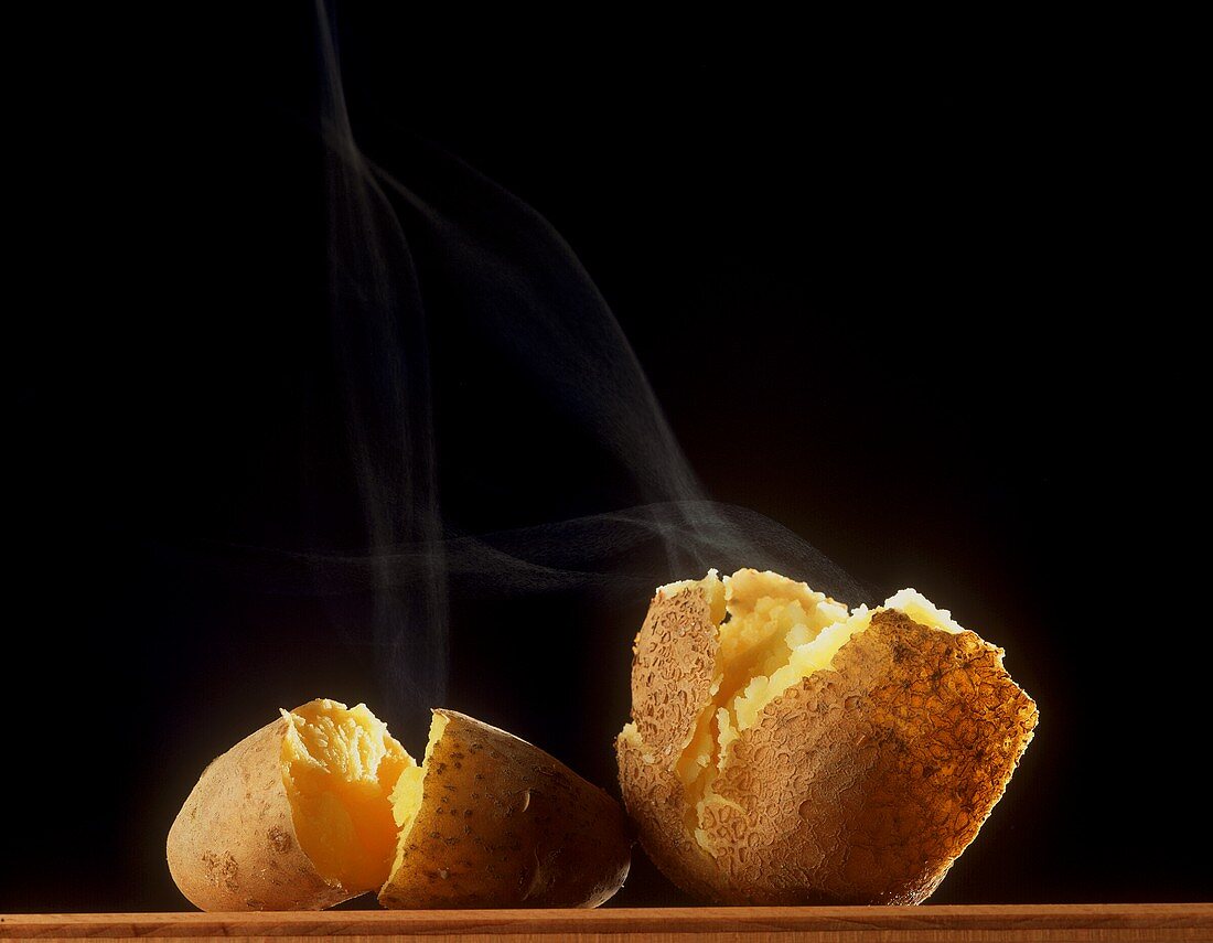 Steaming potato, broken open on black background