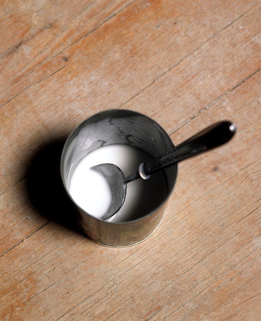 Coconut milk with a spoon in a tin
