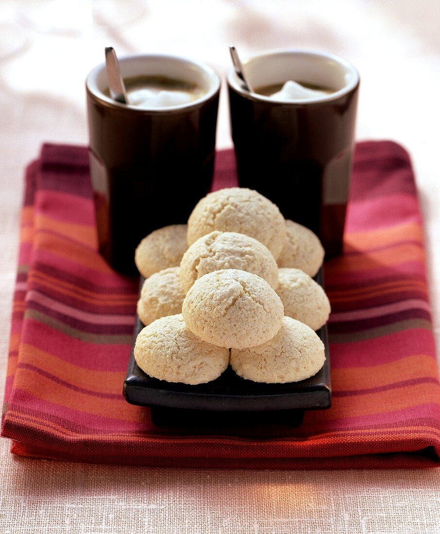 Amaretti (almond macaroons) in front of 2 mugs of white coffee