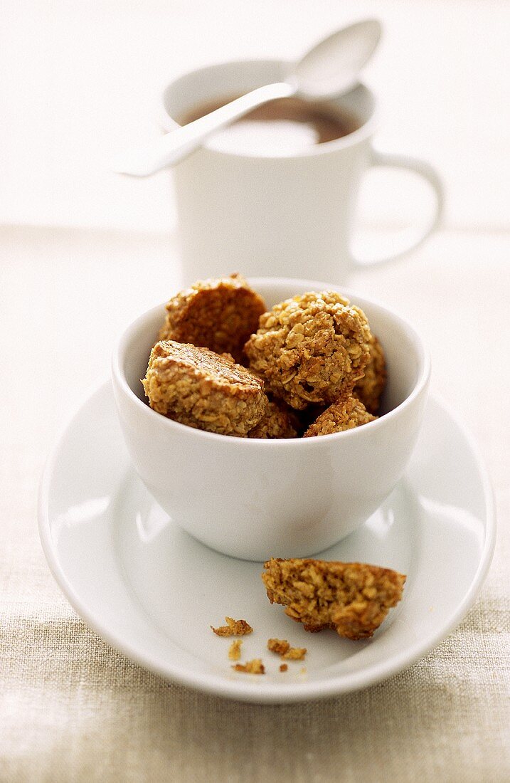 Muesli biscuits in a bowl, cup of coffee behind