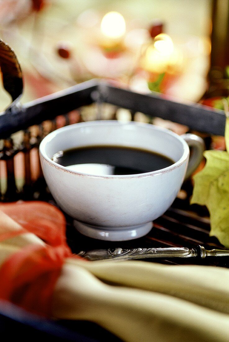 Cup of black coffee on tray with autumn decoration