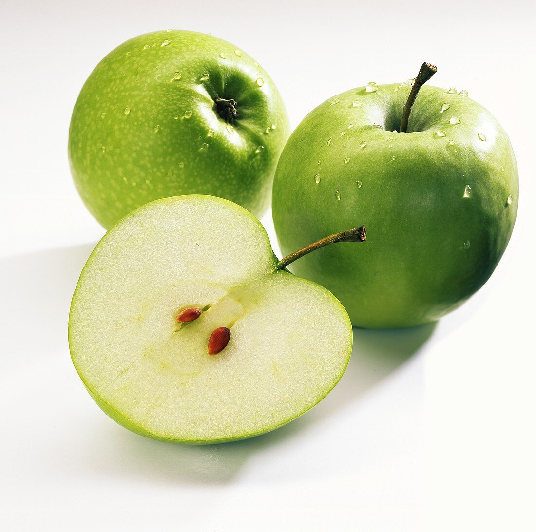 One half and two whole Granny Smith apples