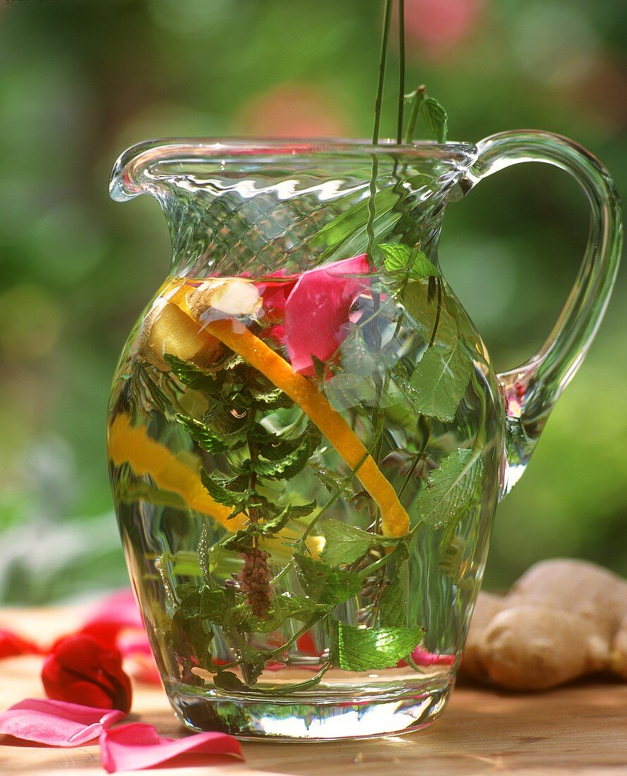 Summery herb tea with fresh herbs in glass carafe
