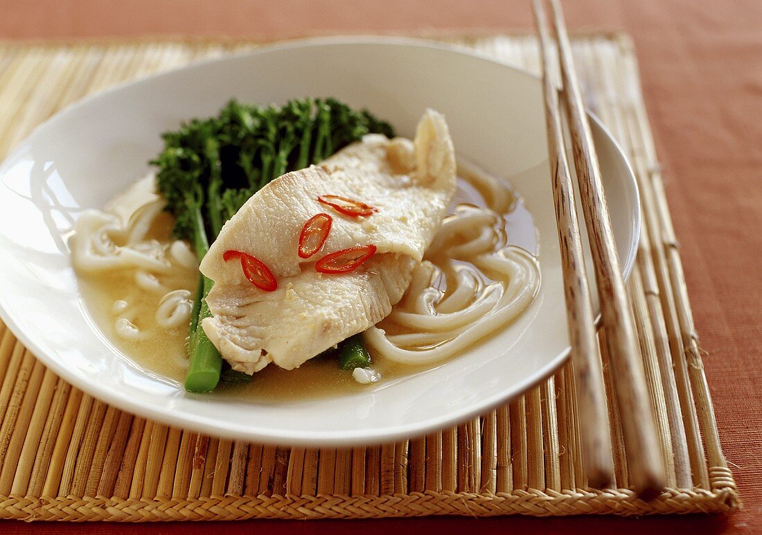 Asian soup with fish, broccoli and udon noodles
