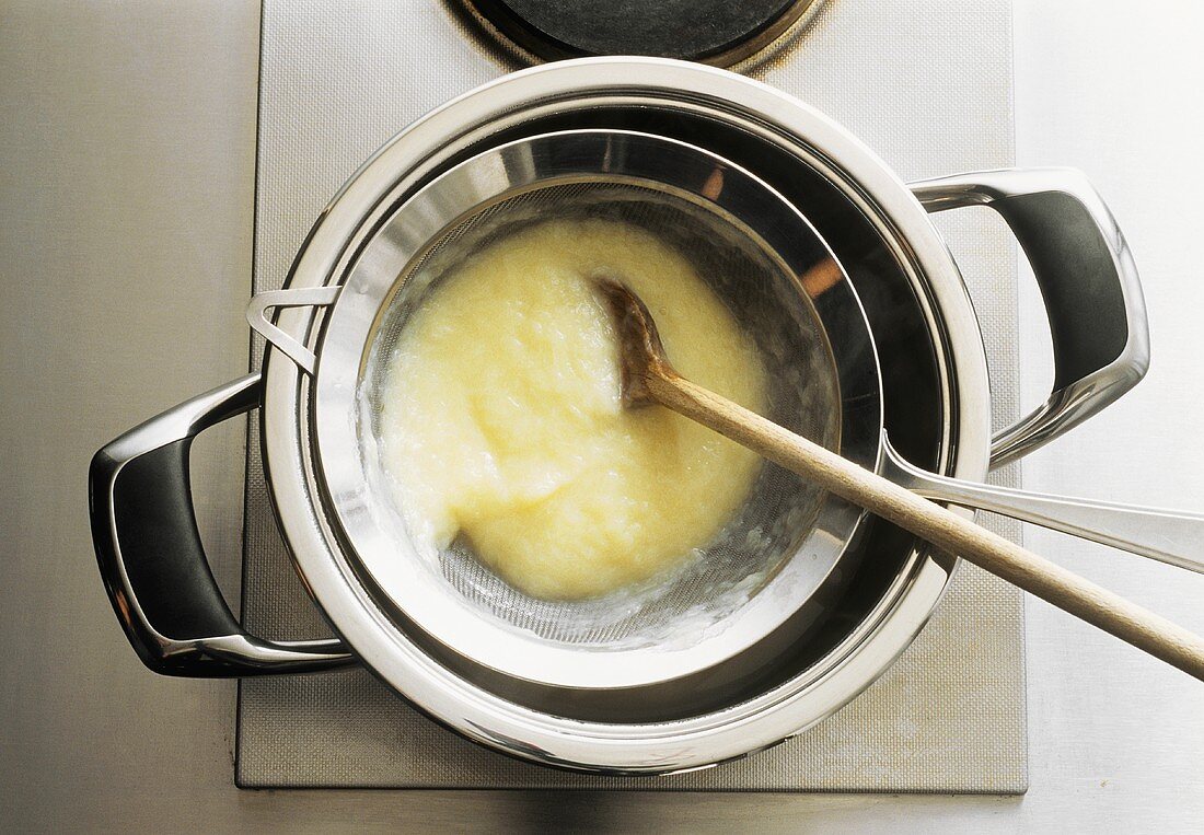 Making creamed soup: straining the soup through a sieve