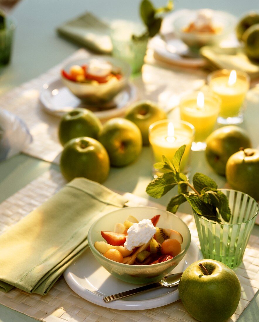 Laid table with fruit salad and green apples
