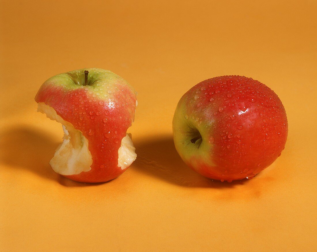 One whole apple and an apple with a bite taken