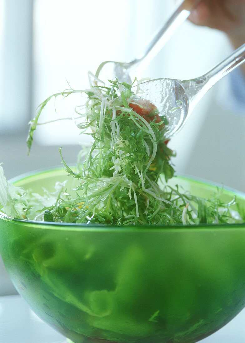Mixing green salad with salad servers