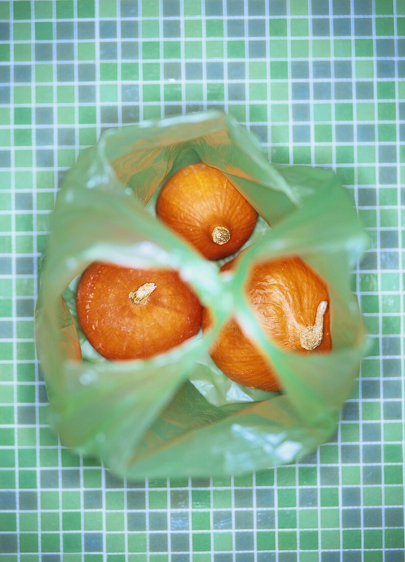 Drei Kürbisse (Sorte Hokkaido) in einer Plastiktüte