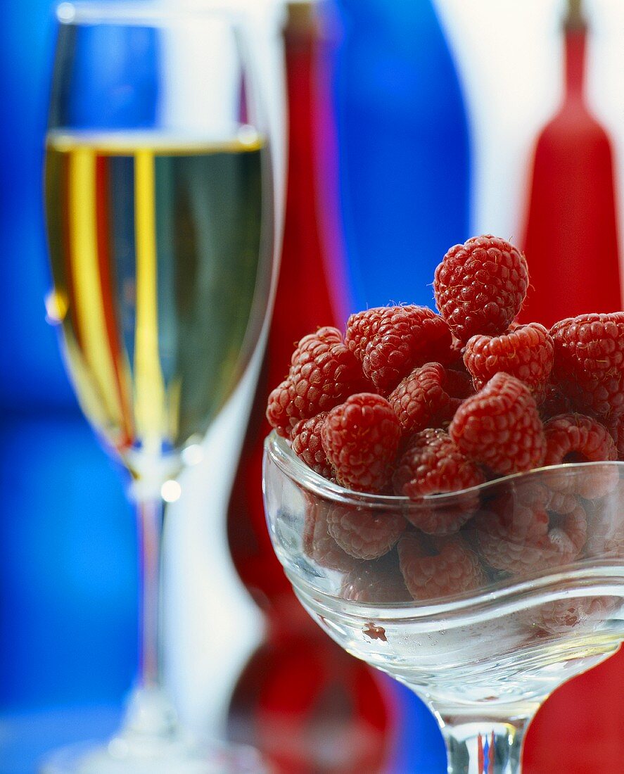Fresh raspberries in glass bowl and a glass of champagne