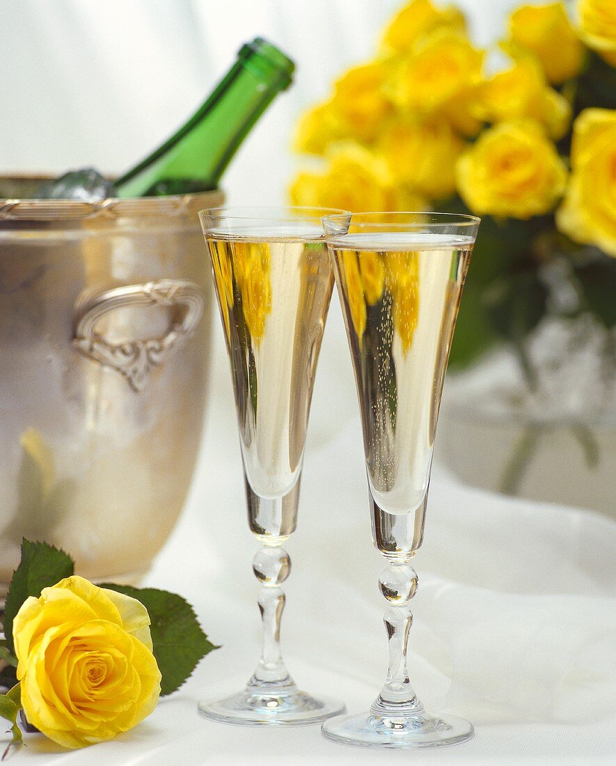 Two glasses of champagne, champagne bucket with bottle & roses