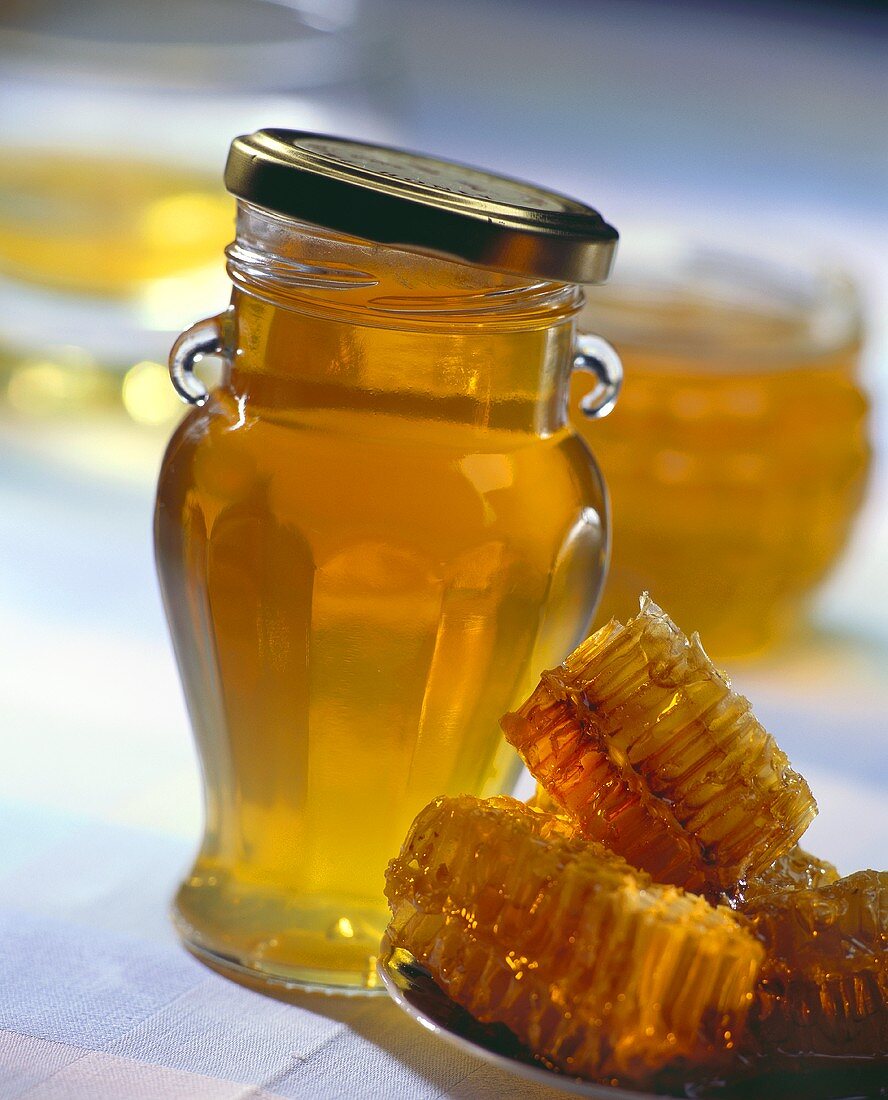Honeycombs beside honey in screw-top jar