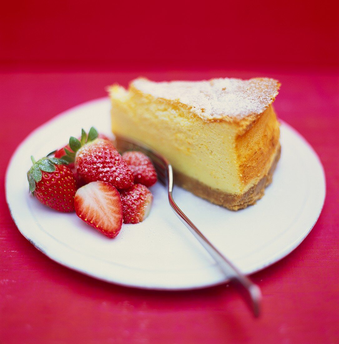 A piece of cheesecake and fresh strawberries