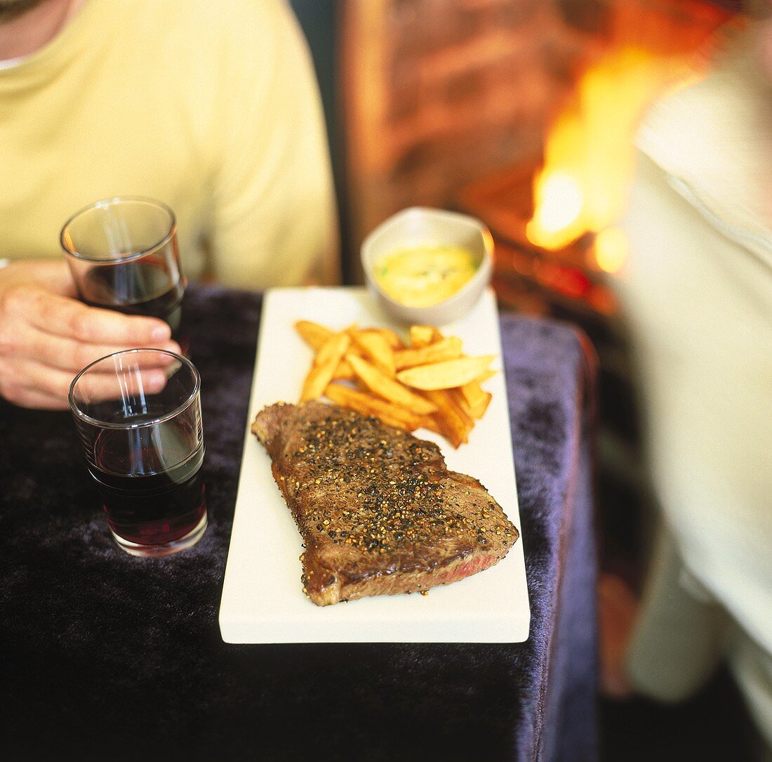 Steak with country potatoes, people & fireplace in background