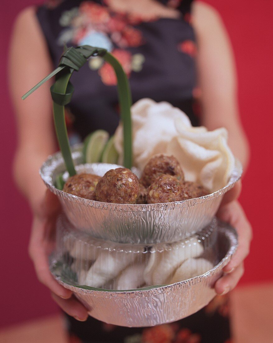 Woman holding Asian style meatballs with prawn crackers 