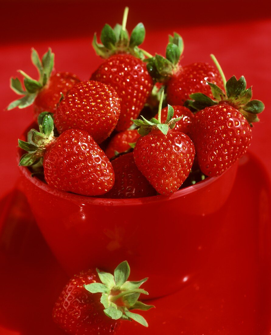 Fresh strawberries in a red plastic beaker