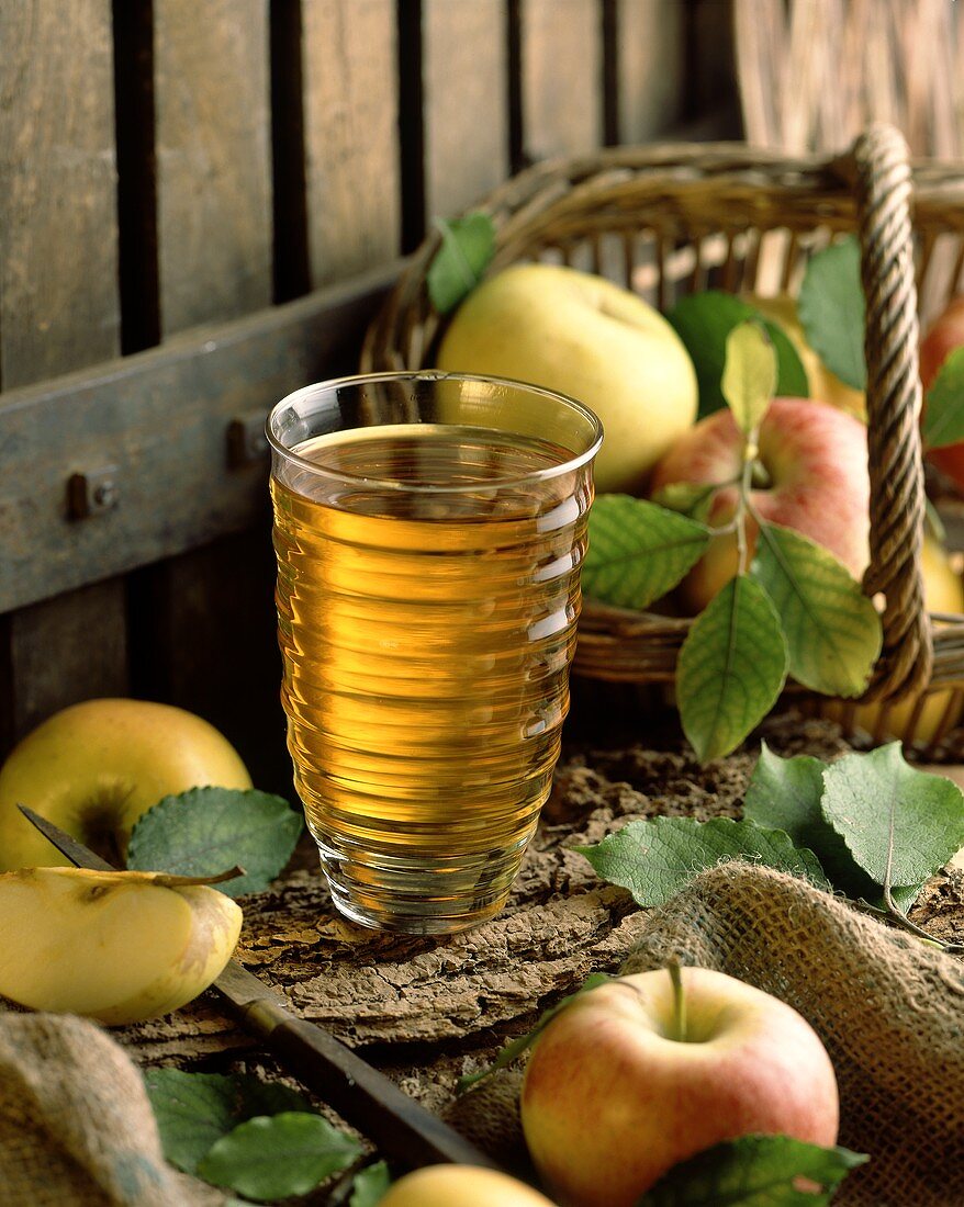 A glass of apple juice with apples as decoration