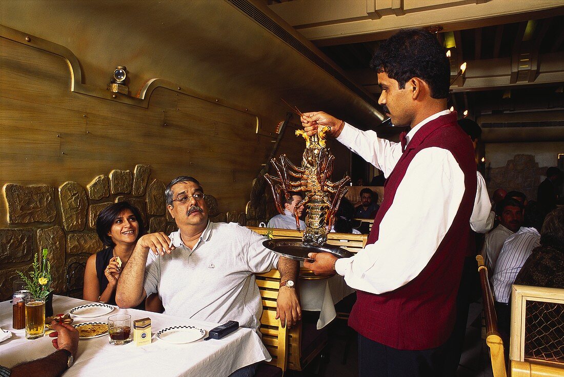 Waiter showing guests a spiny lobster before cooking