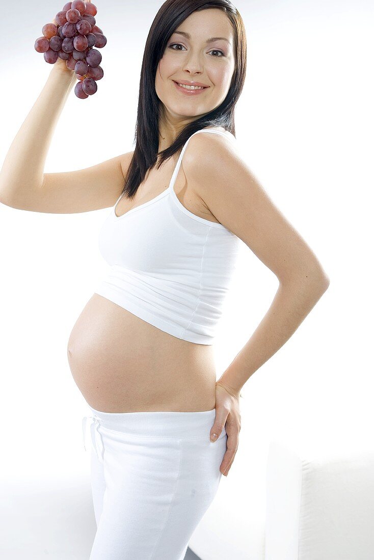 Pregnant woman holding red grapes in her hand
