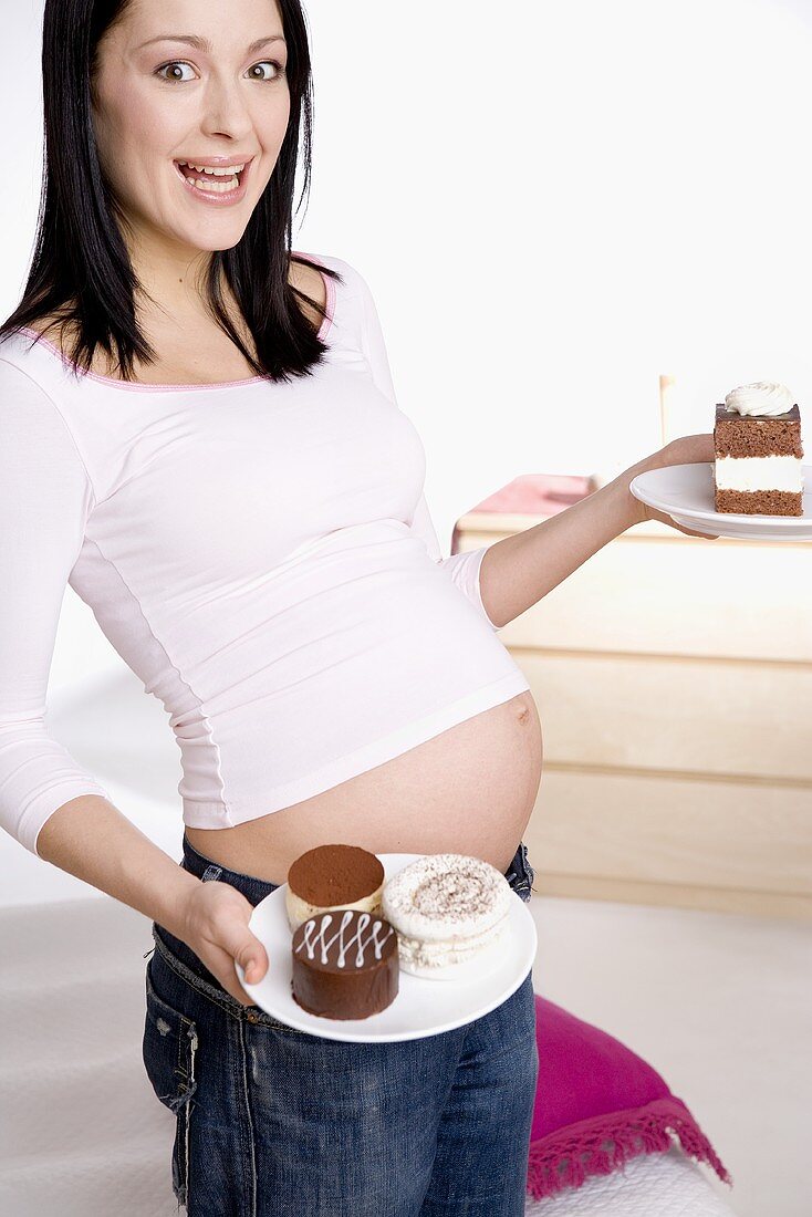 Schwangere Frau, Kuchenstücke auf Teller haltend