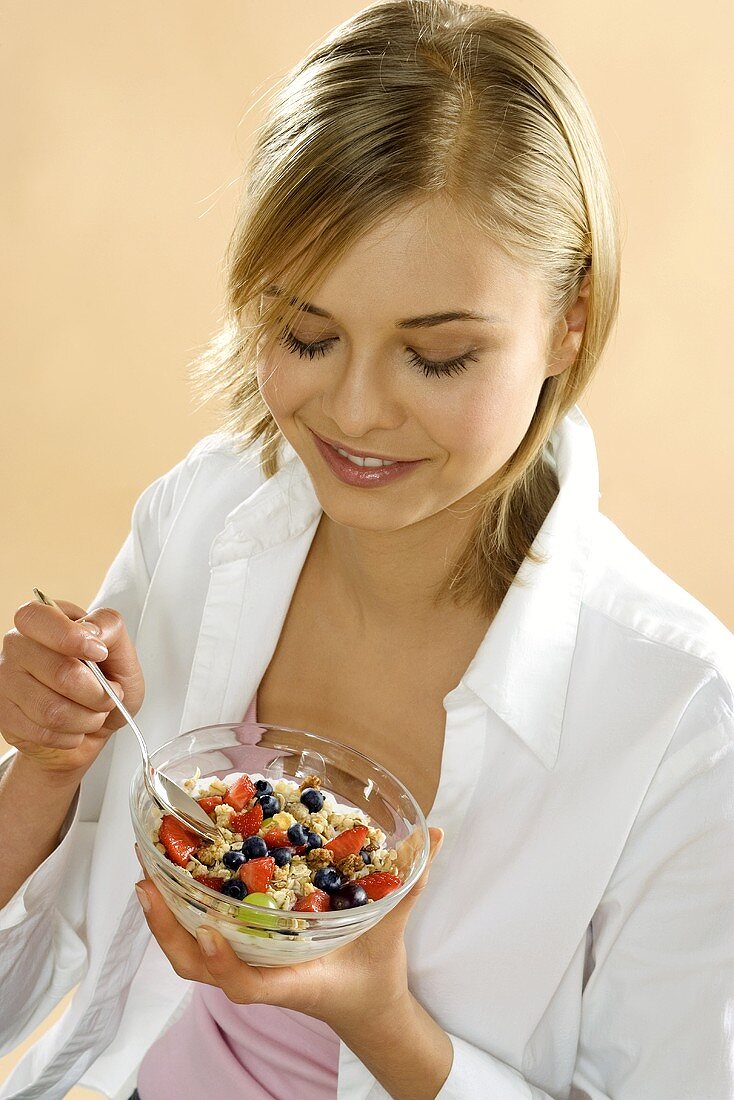 Young woman holding bowl of fruit muesli
