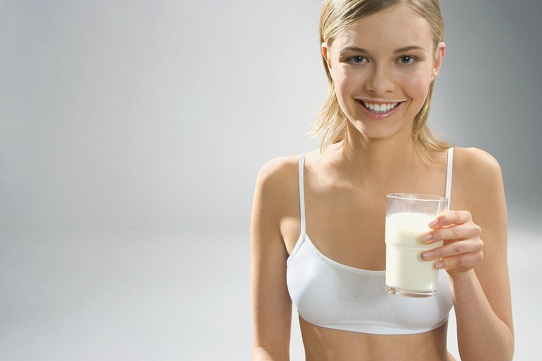 Young woman with milk around  mouth, holding a glass of milk
