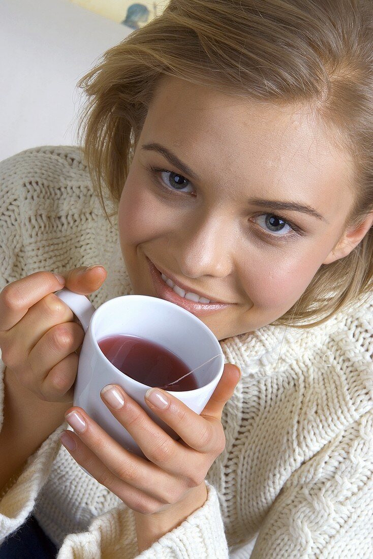 Junge Frau hält Becher mit Heissgetränk in der Hand