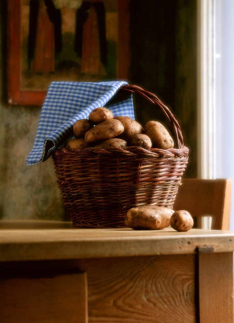 Freshly harvested potatoes in a basket on kitchen table