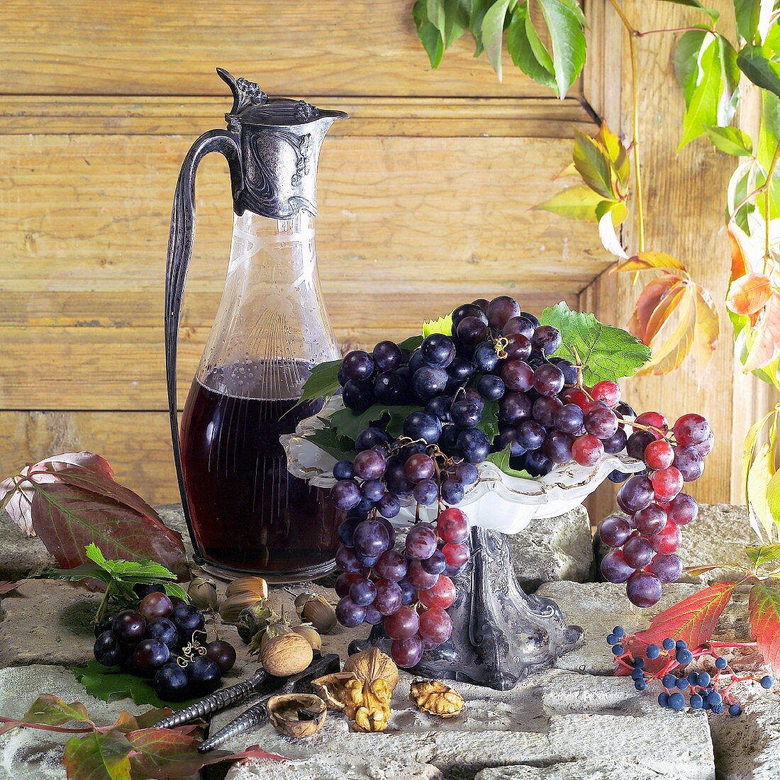 Stillleben mit Rotweintrauben und einer Karaffe Rotwein