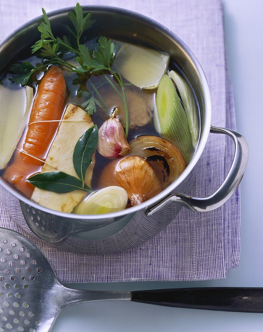 Clear meat broth with vegetables in pan