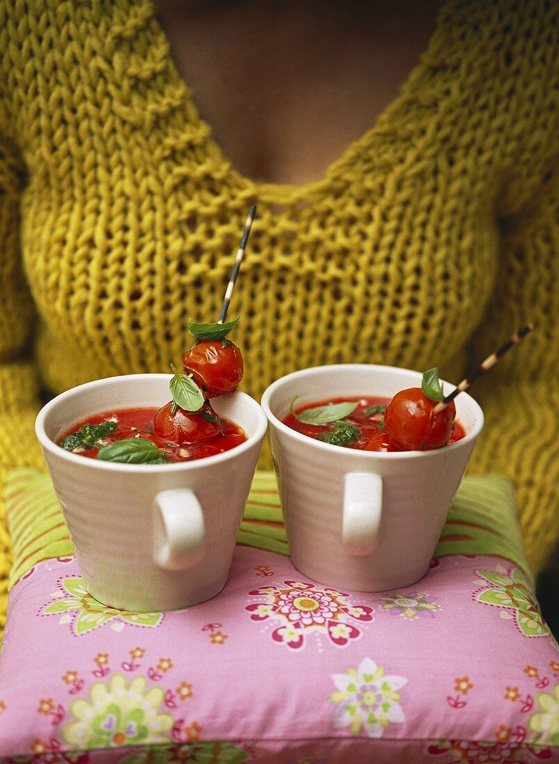 Woman carrying two cups of tomato soup on cushion