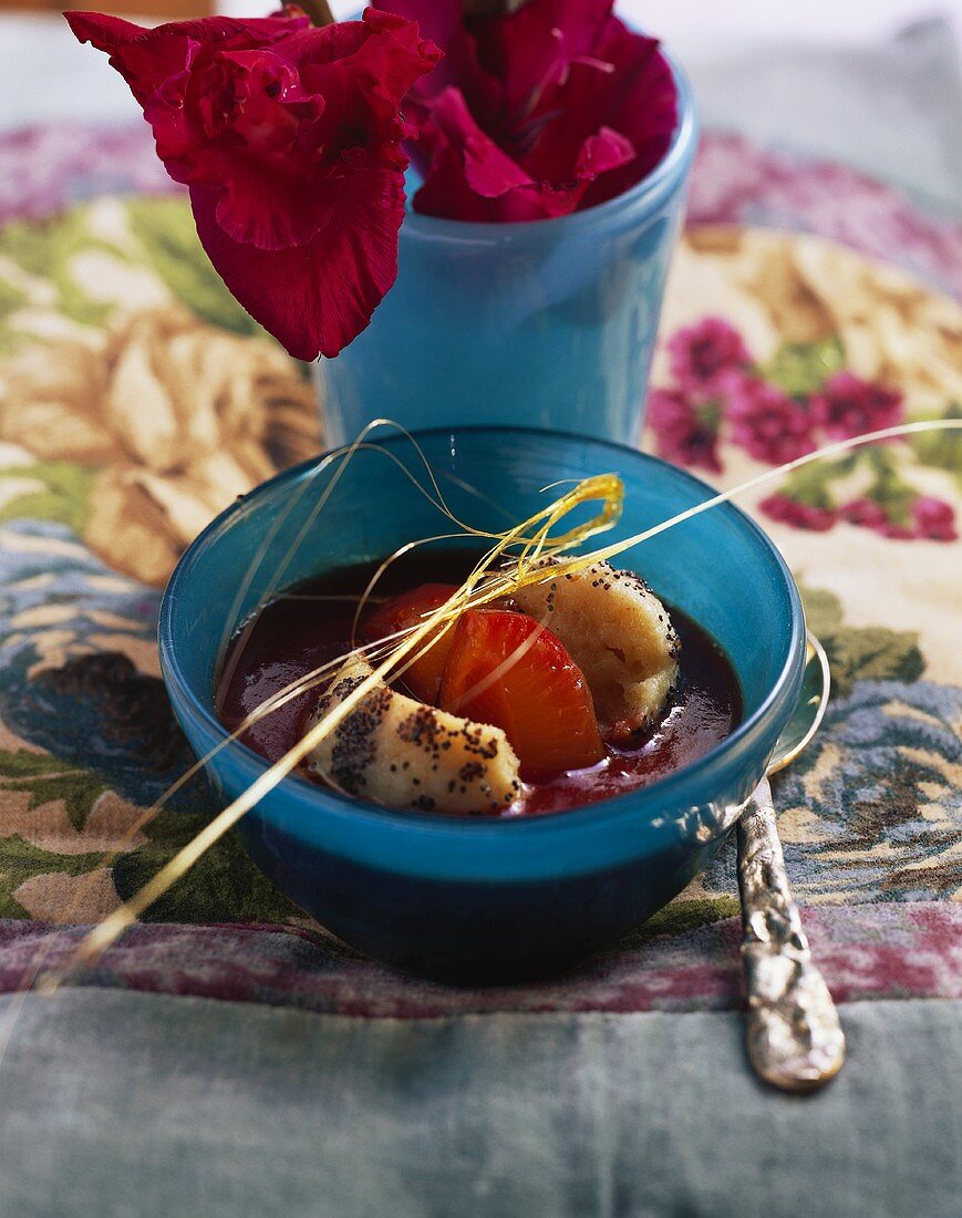 Plum soup with poppy seed dumplings in glass dish