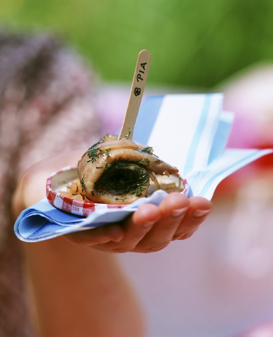 Woman at picnic holding herring with tomato and dill