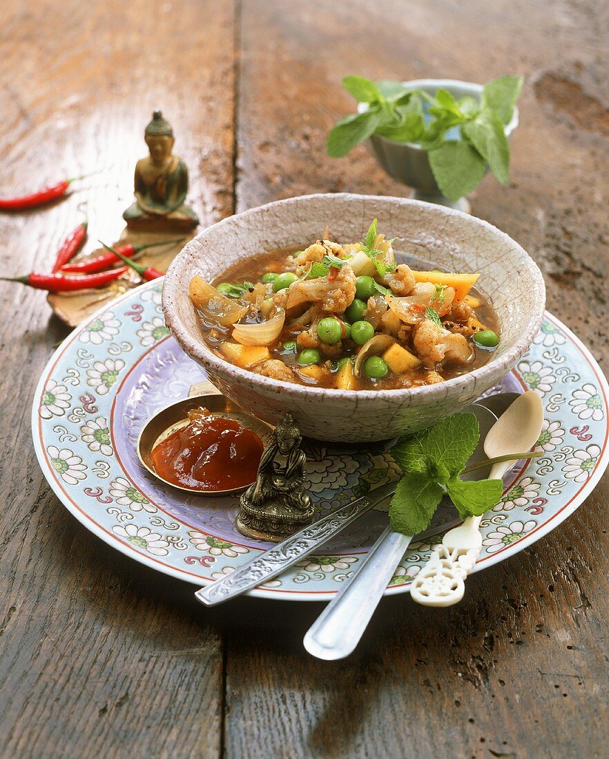 Cauliflower and mango curry with peas in small bowl
