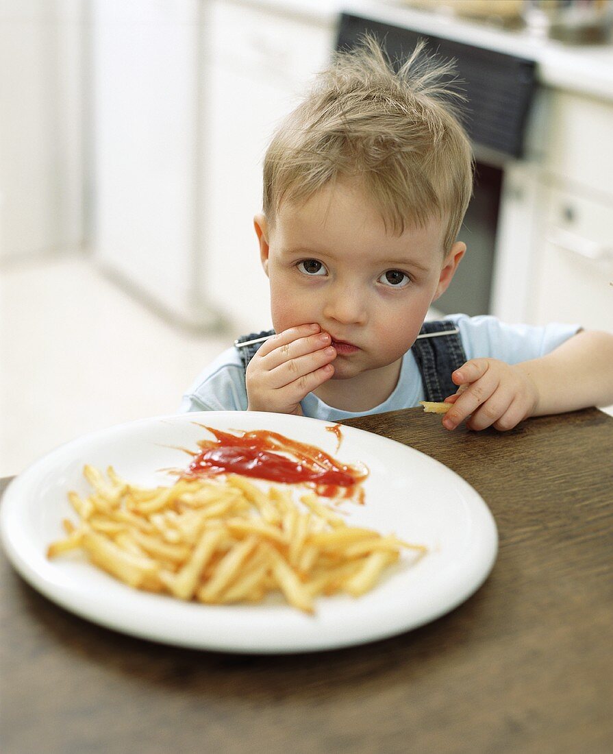 Kleiner Junge Pommes essend