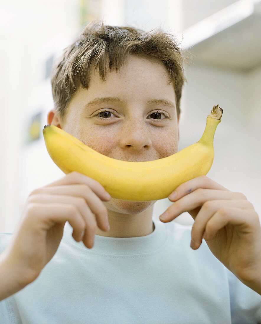 Boy holding banana in front of his face