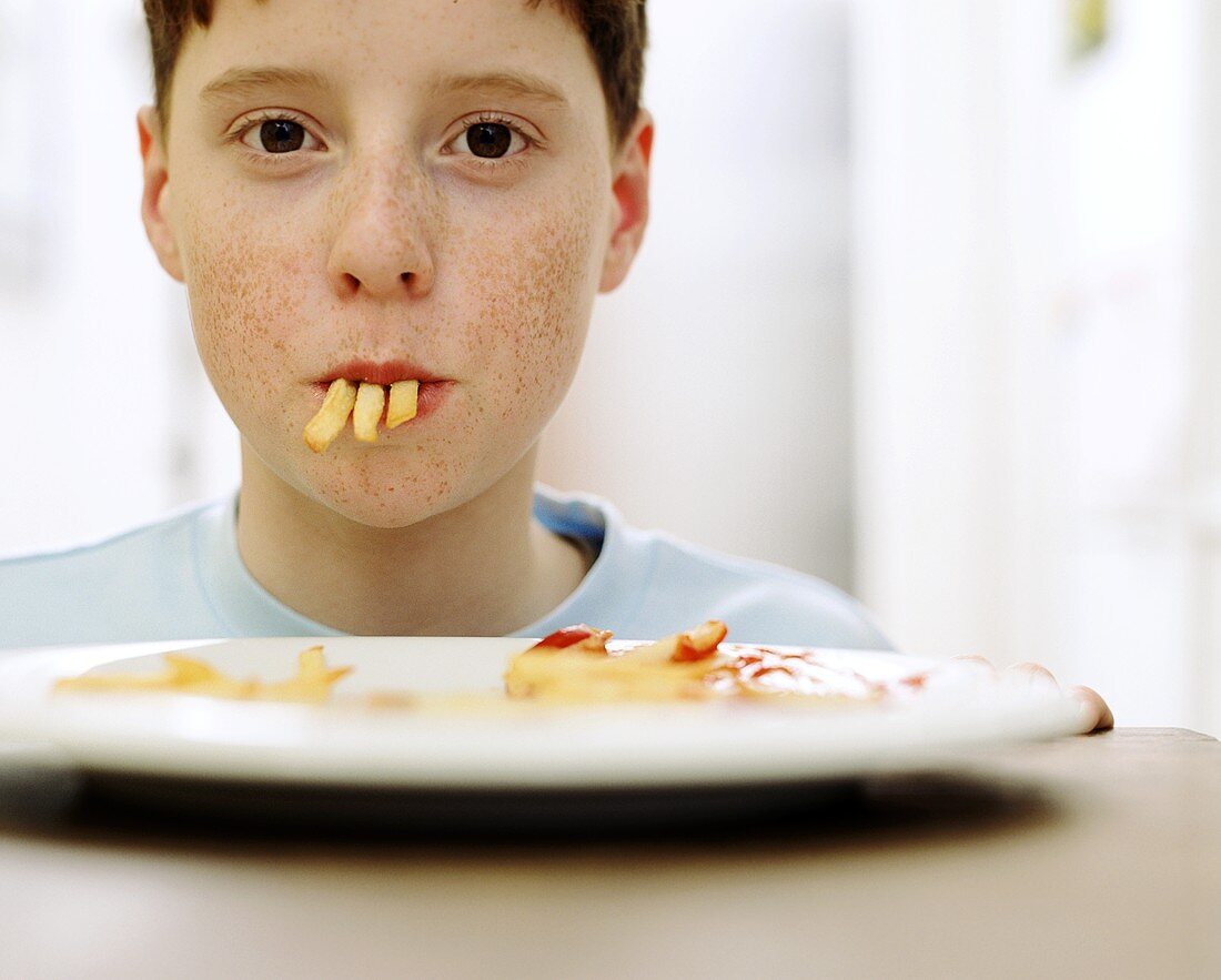 Junge mit drei Pommes im Mund