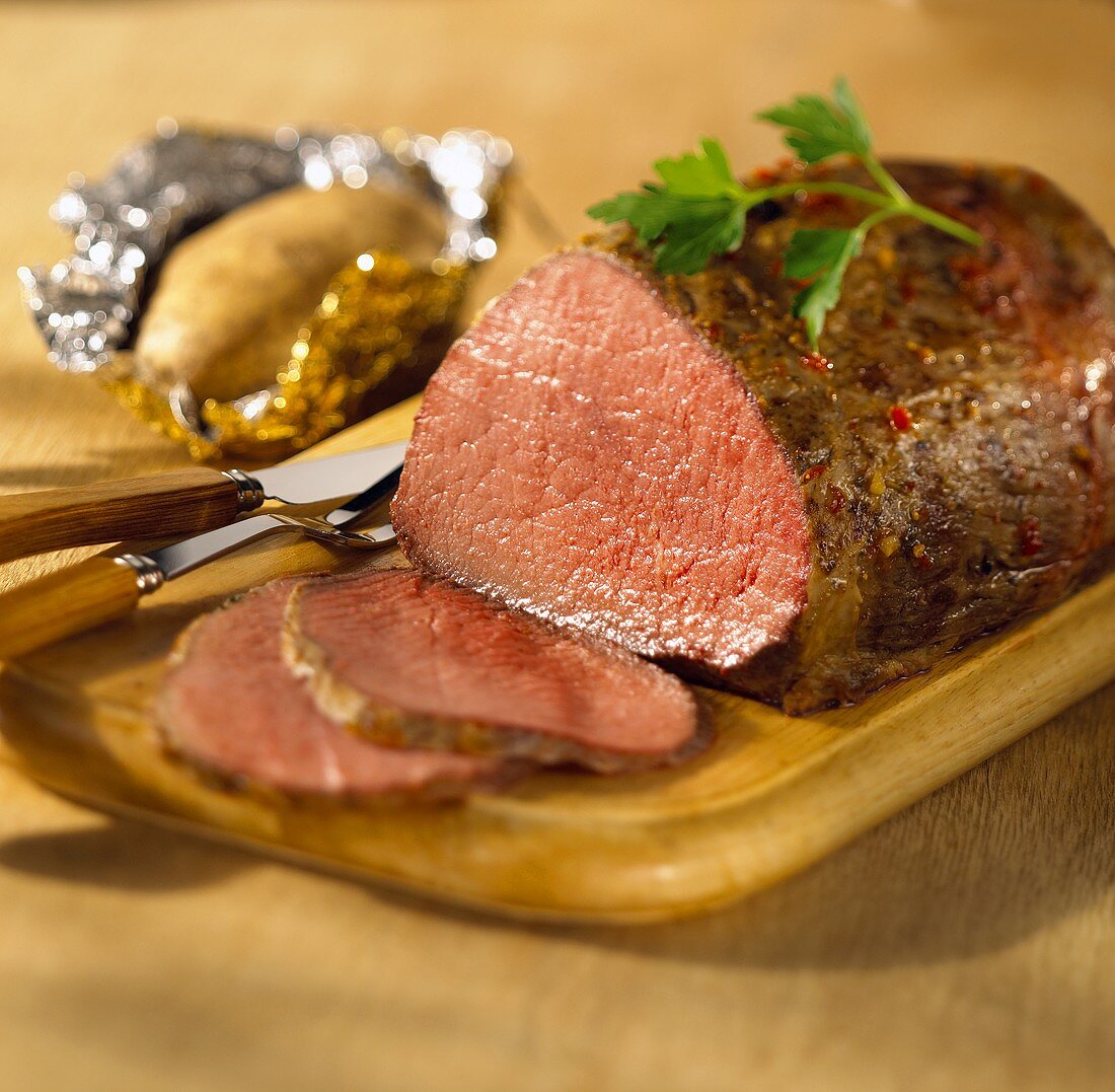 Roast beef, slices carved, on a wooden board