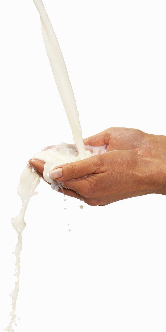 Milk being poured over two hands