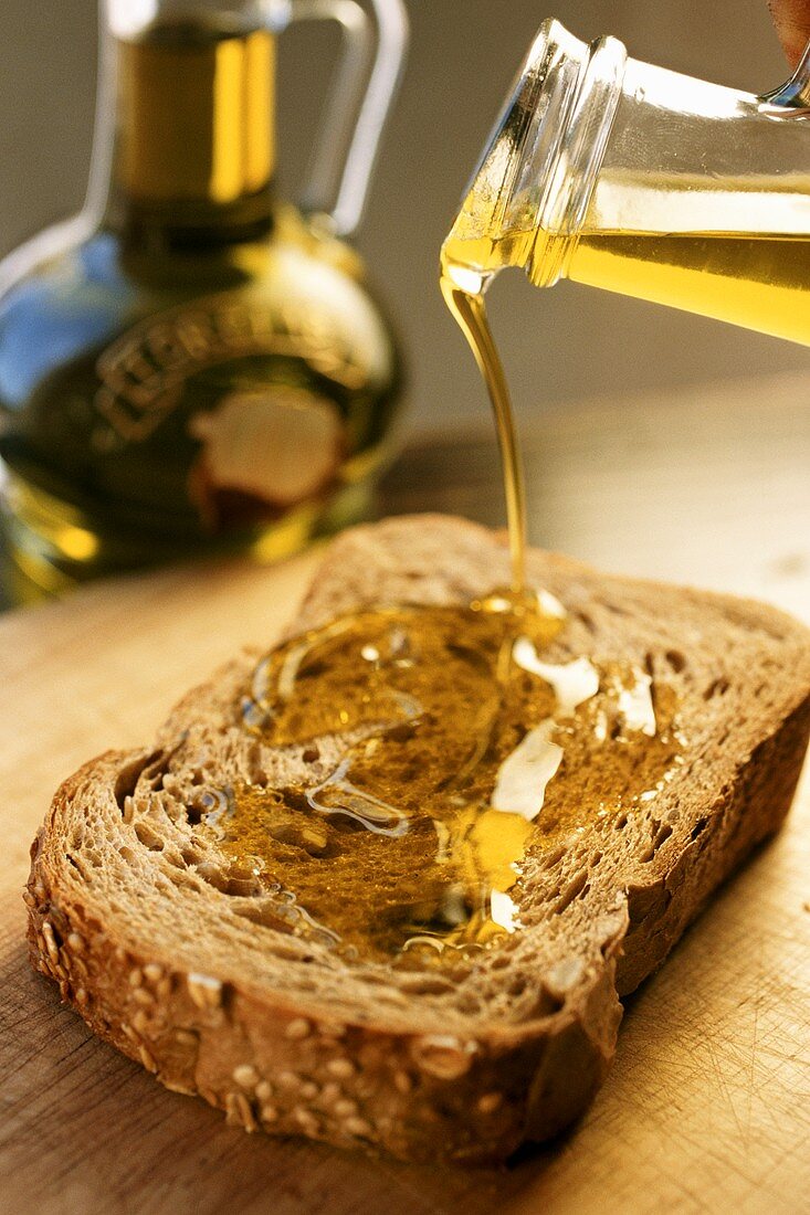 Olivenöl wird auf Brotscheibe gegossen