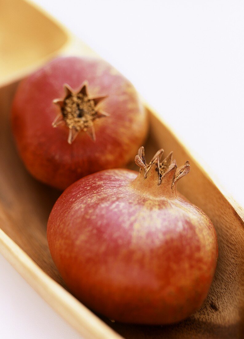 Two pomegranates in wooden bowl