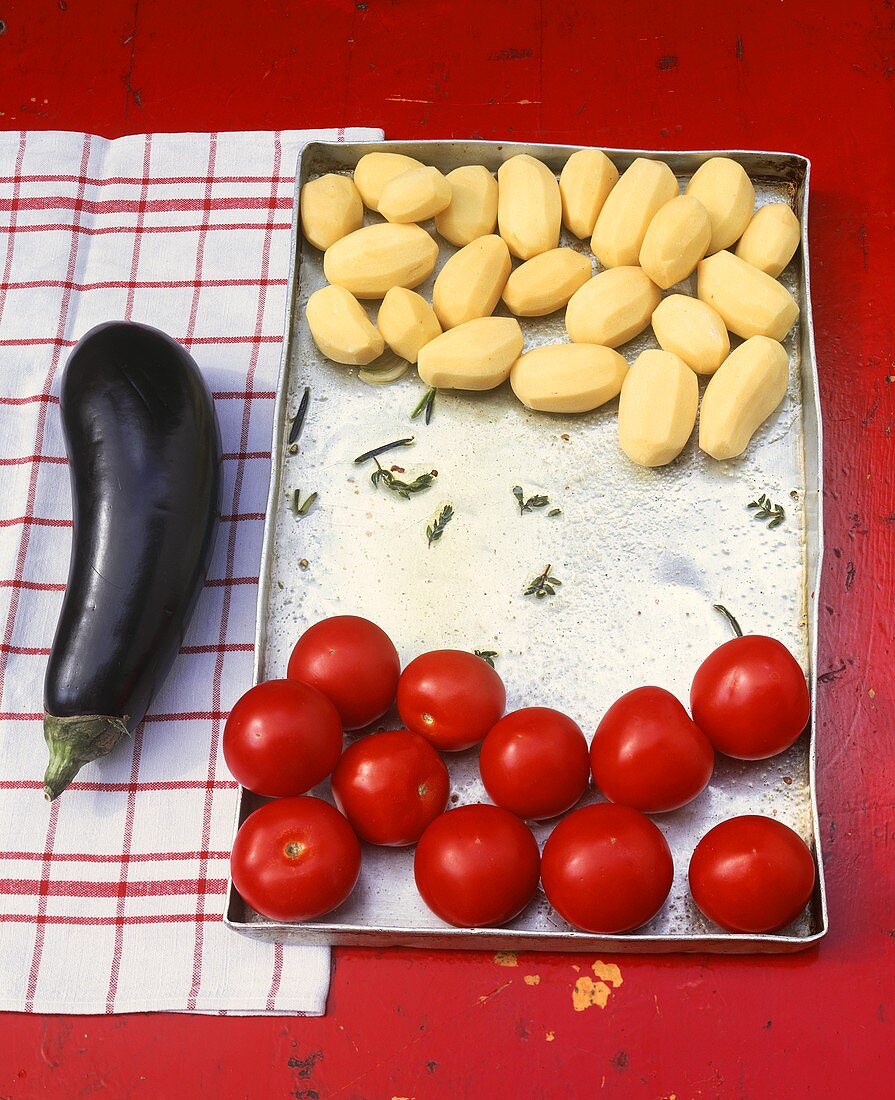 Kartoffeln und Tomaten auf einem Backblech, daneben Aubergine