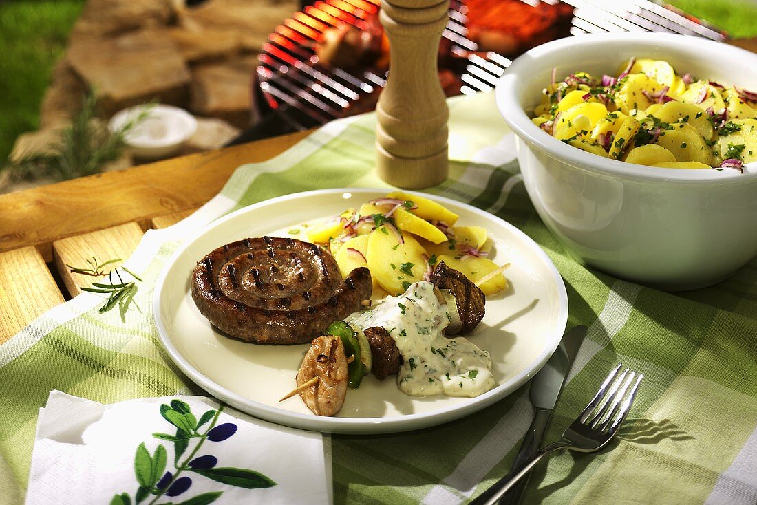 Sausage coil and meat kebab with potato salad