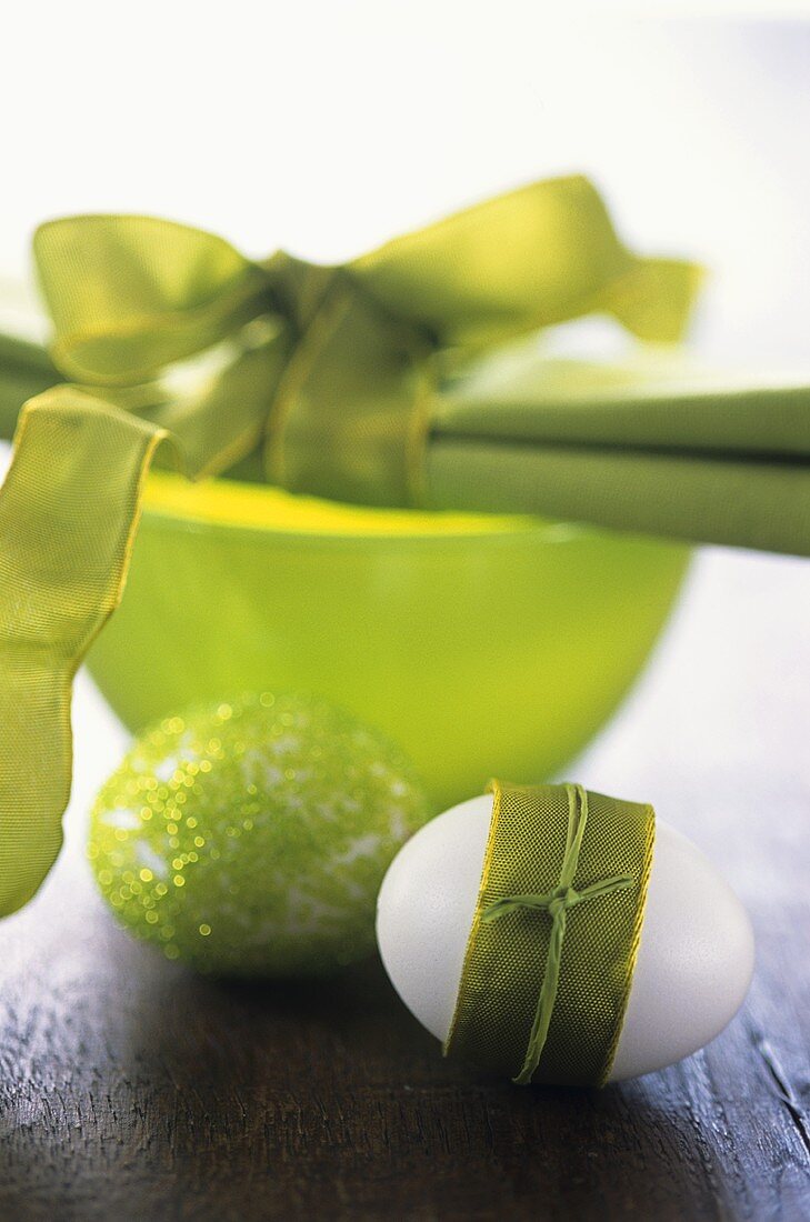 Two Easter eggs and bowl with fabric napkin and bow