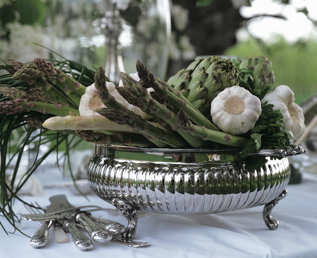 Silver bowl with green asparagus, garlic & artichokes
