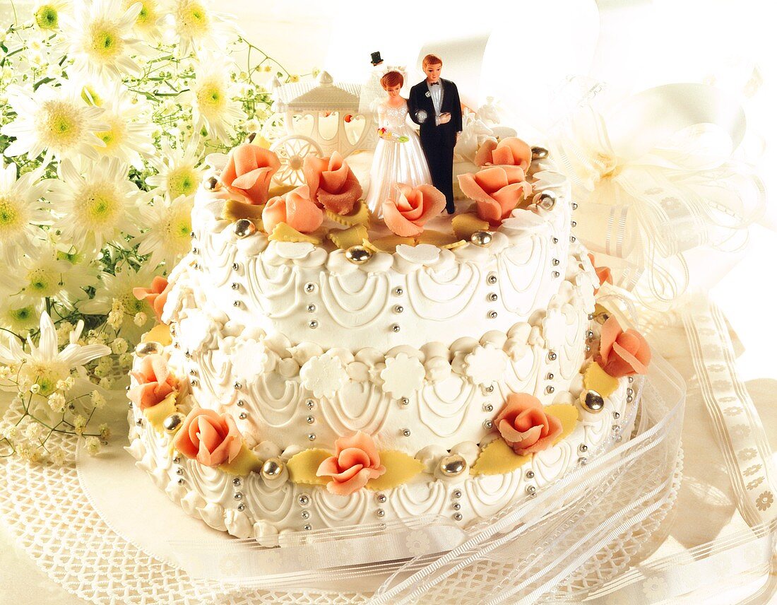 Three-tiered white wedding cake with bride and groom figures