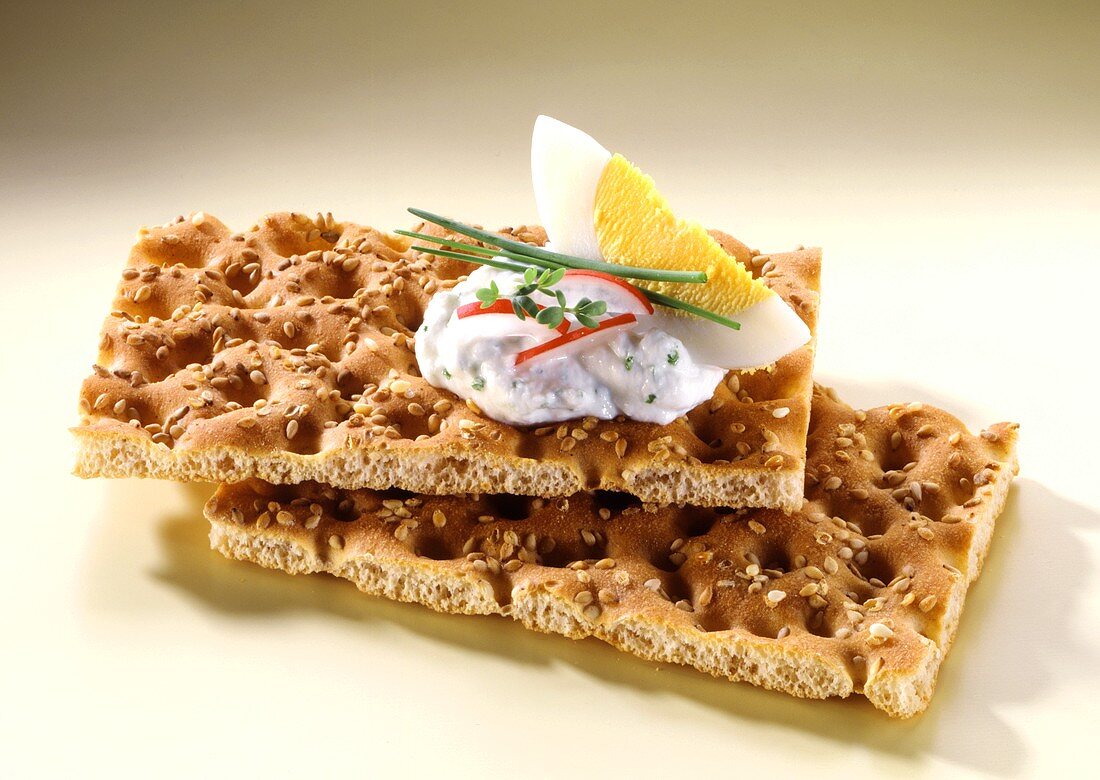 Two slices of sesame crispbread with herb quark and egg