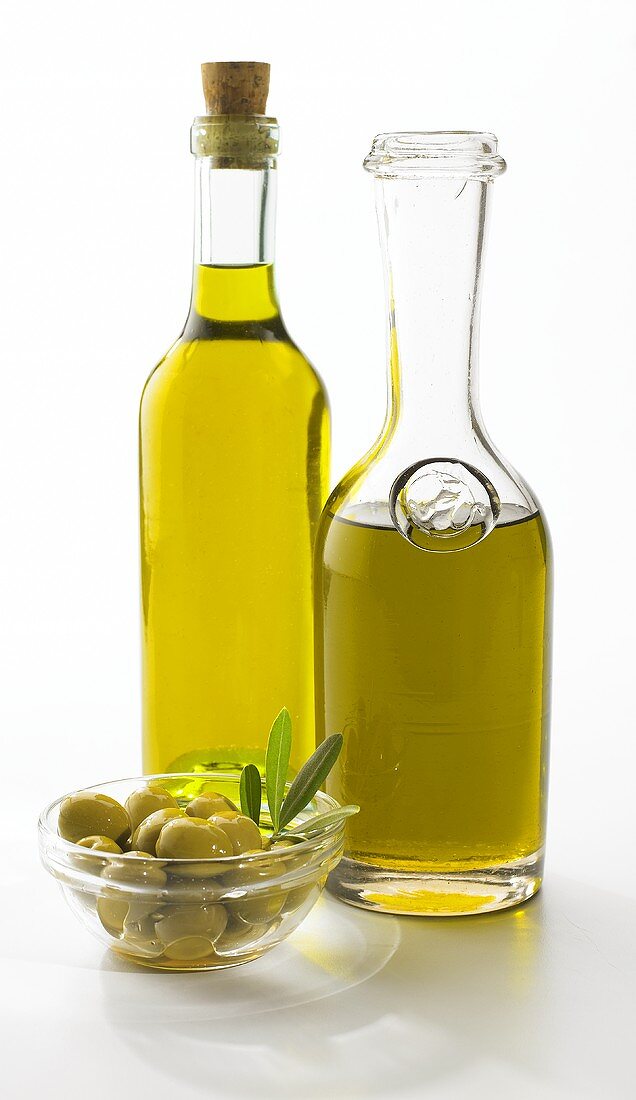 Ein Schälchen grüne Oliven und zwei Flaschen Olivenöl