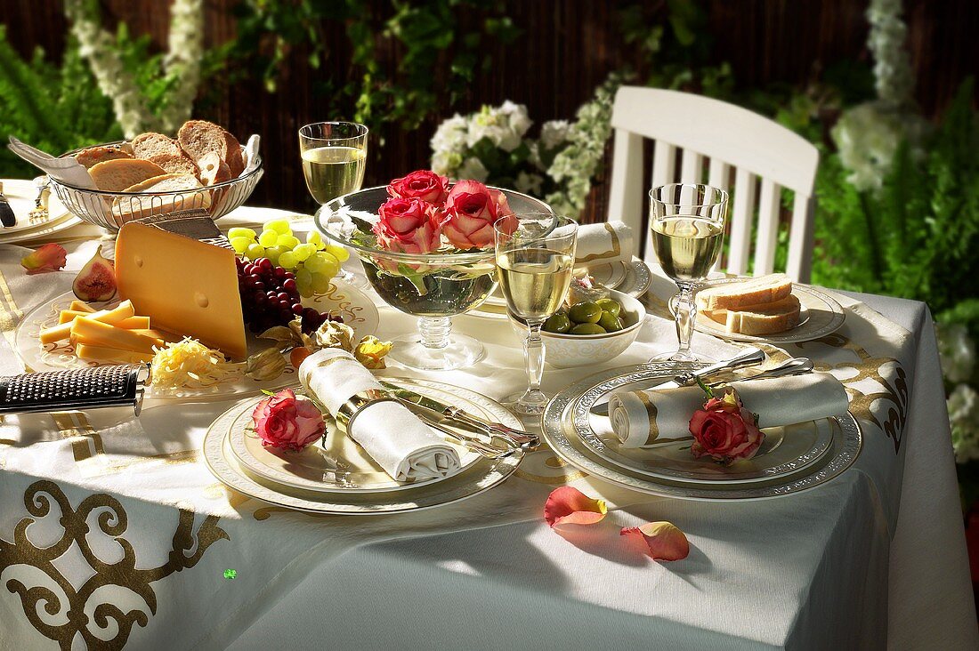 Laid table with roses, cheese platter, olives etc.